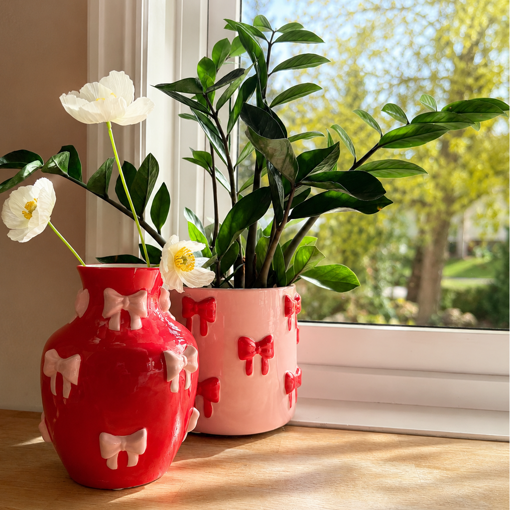 Sett med vase og potte i rosa og rød med sløyfer, perfekt for fargerik og søt jentete dekor i et fargerikt hjem