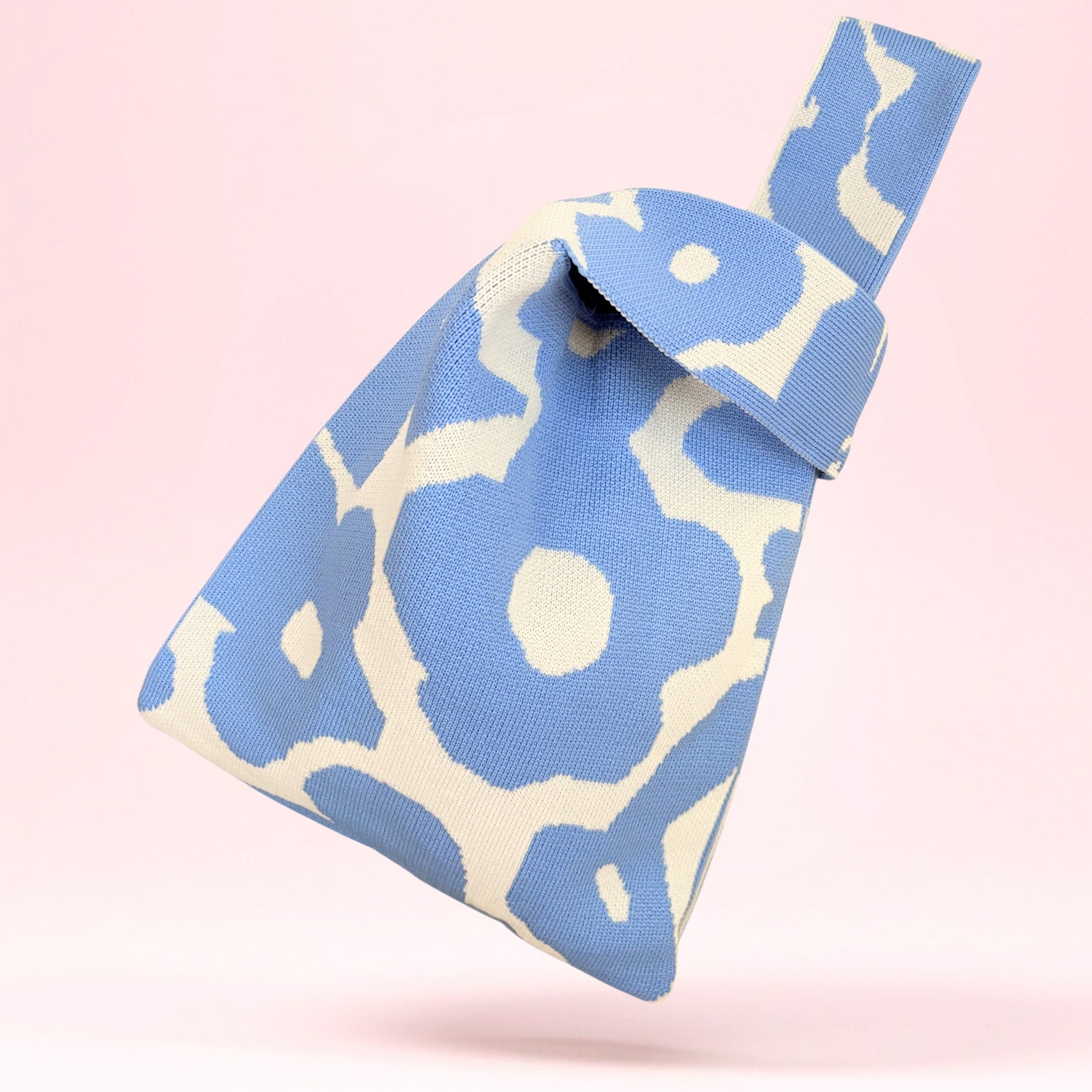 Studiofoto av strikket totebag med lyseblå retro blomsterdesign og kremfargede håndtak.