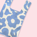 Nærbilde av strikket totebag som viser detaljene i det lyseblå retro blomsterdesignet.