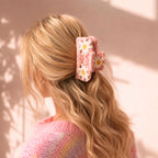 Blond modell med rosa crochet hårklype med blomsterdetaljer i mykt bølgete hår og varm pastel aesthetic.