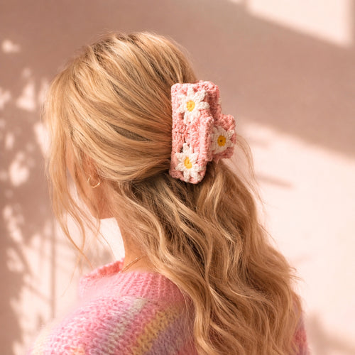 Blond modell med rosa crochet hårklype med blomsterdetaljer i mykt bølgete hår og varm pastel aesthetic.